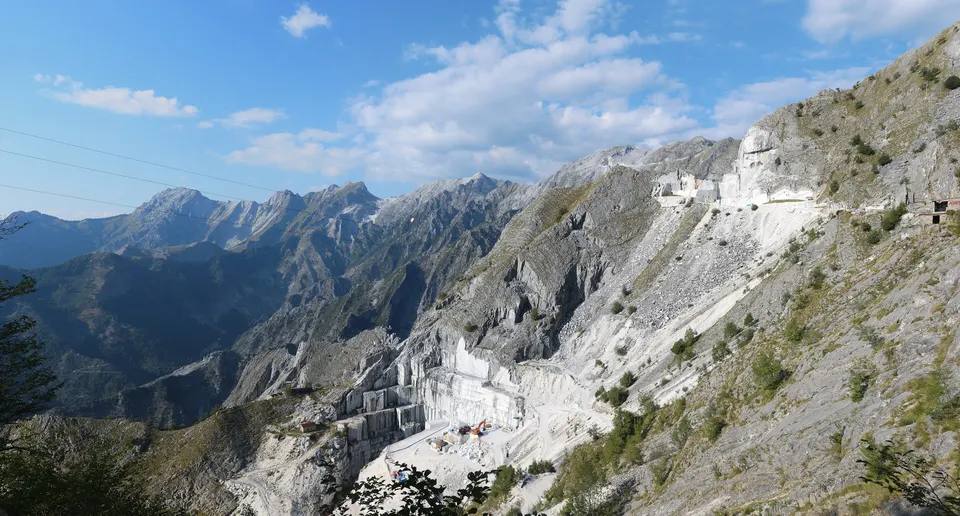 White marble quarry cut into a mountainside under a blue sky