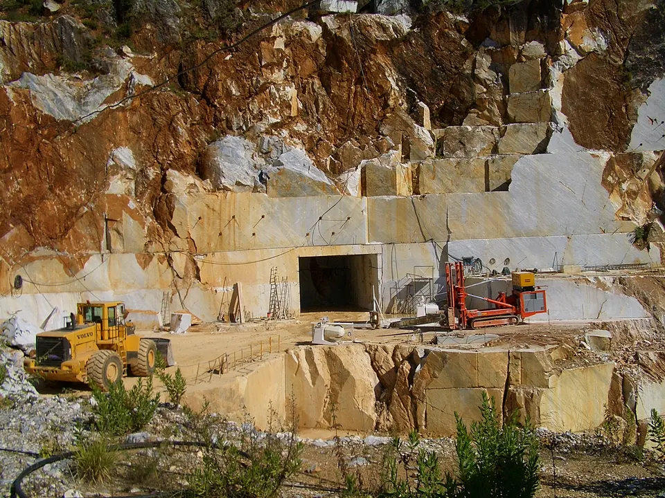 Machinery working at an open white marble quarry face